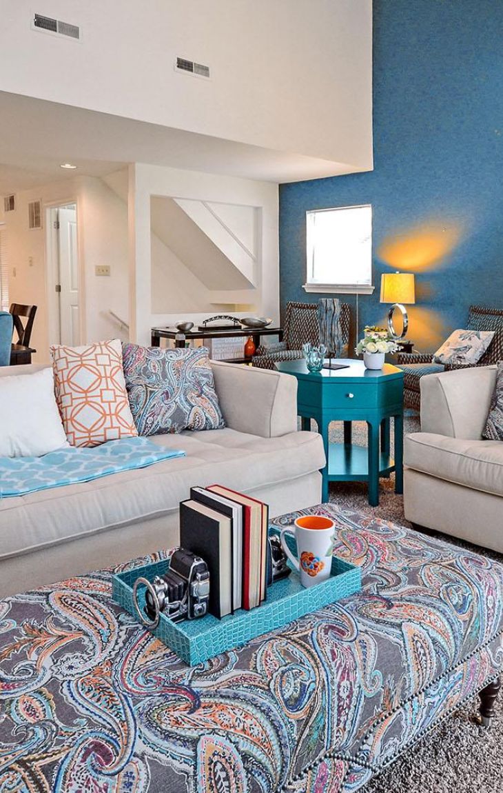 Modern living room with blue accents, patterned pillows, and a cozy seating area near a fireplace.