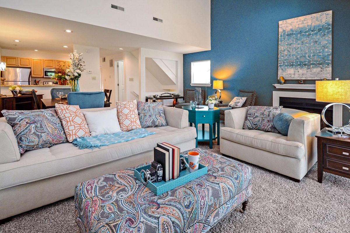 Modern living room with blue accents, patterned pillows, and a cozy seating area near a fireplace.